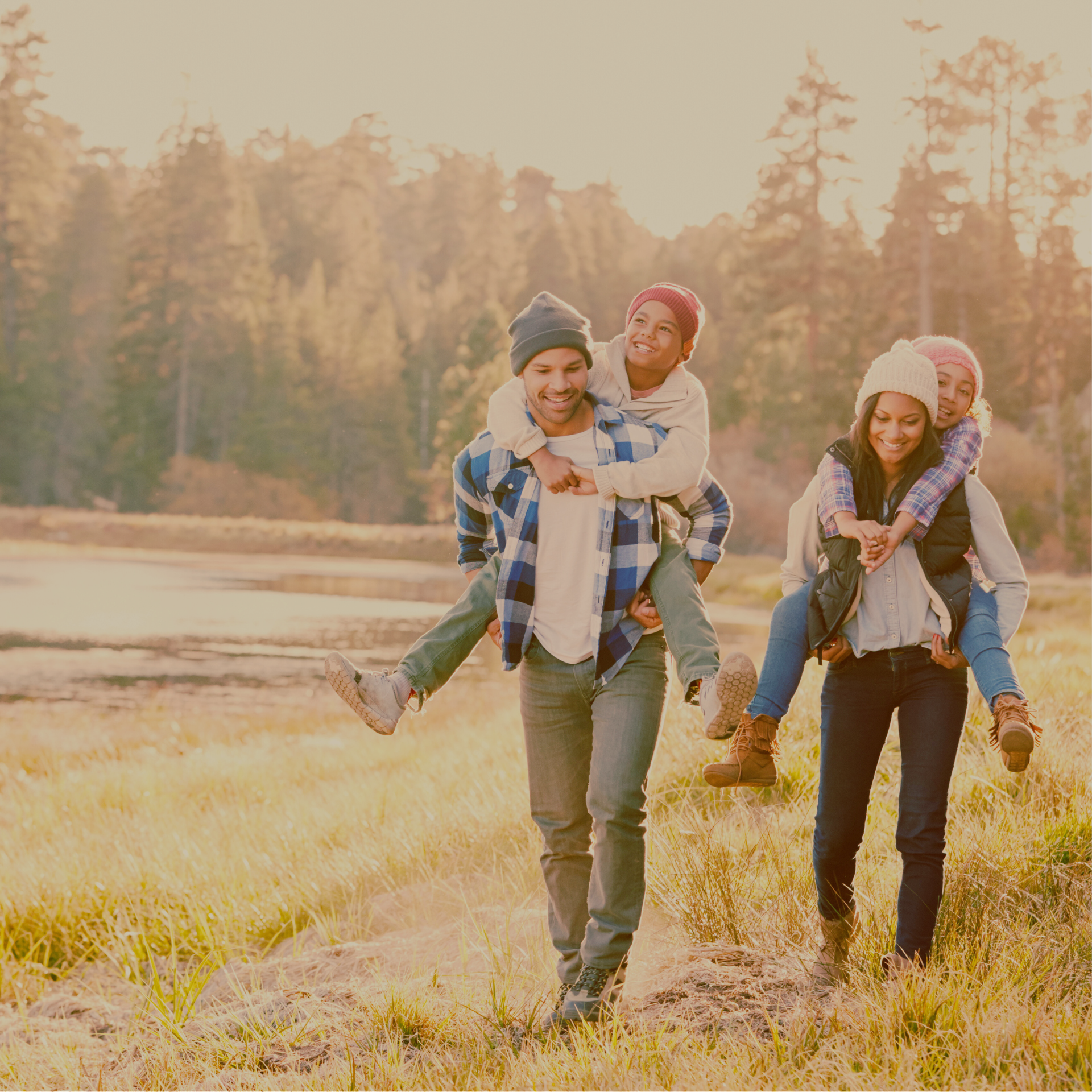Mom and dad giving their kids piggyback rides while they hike together outdoors in a field.