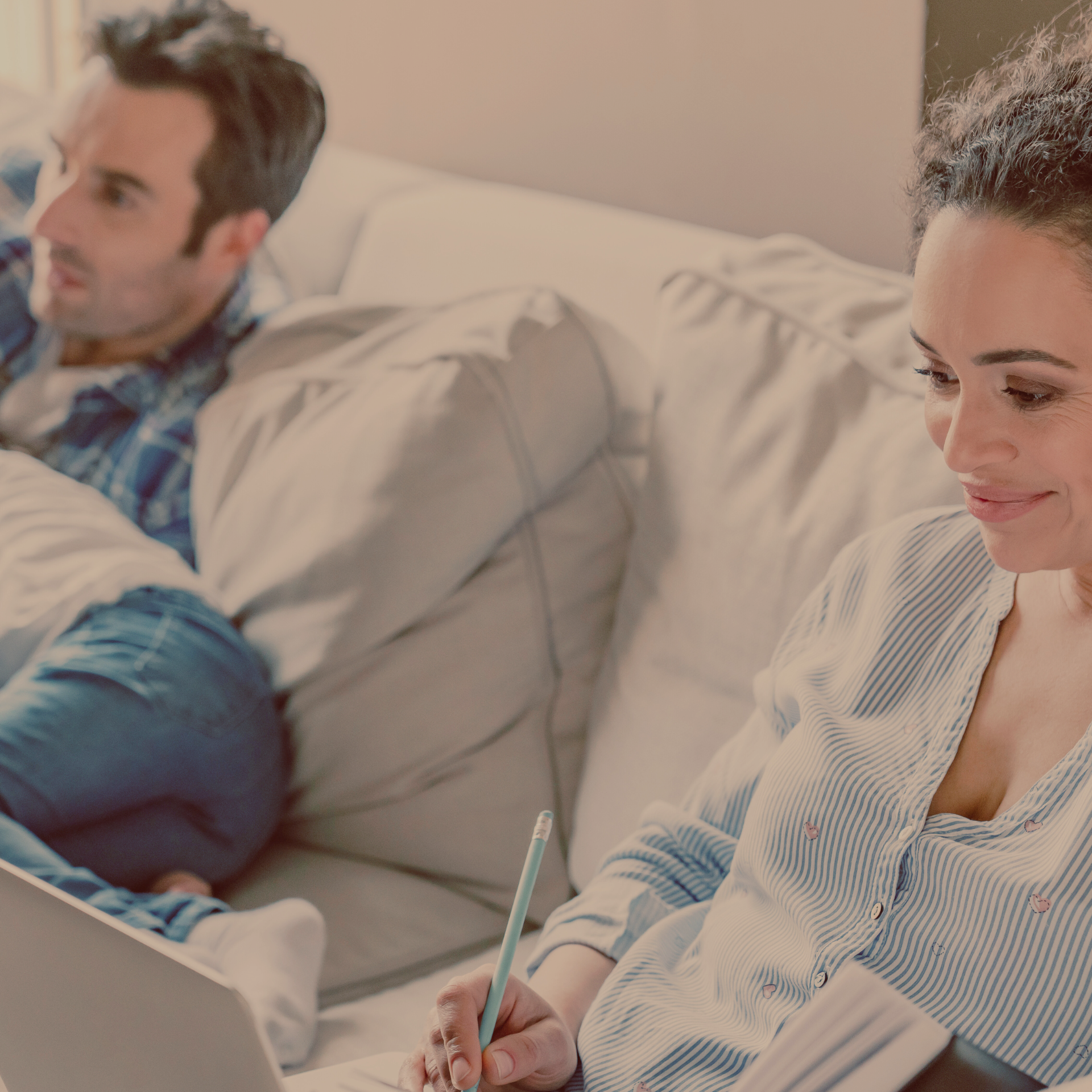 Family spending time together on the couch while the mom does research on a laptop.