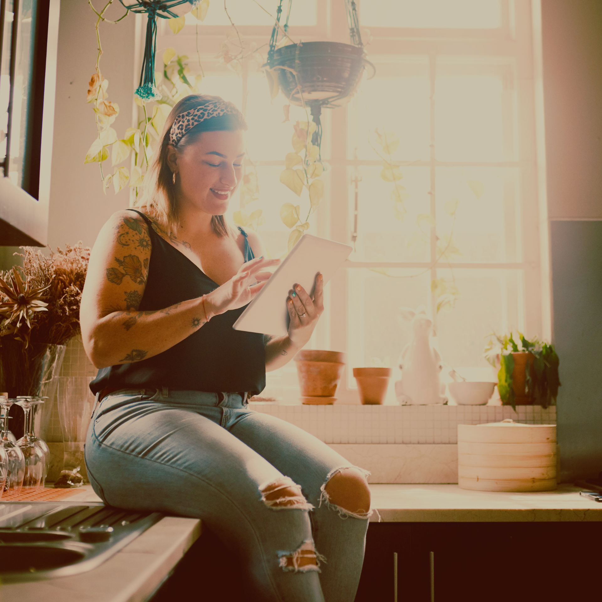 Woman sitting on the counter in her kitchen while using her tablet to complete the age calculator.