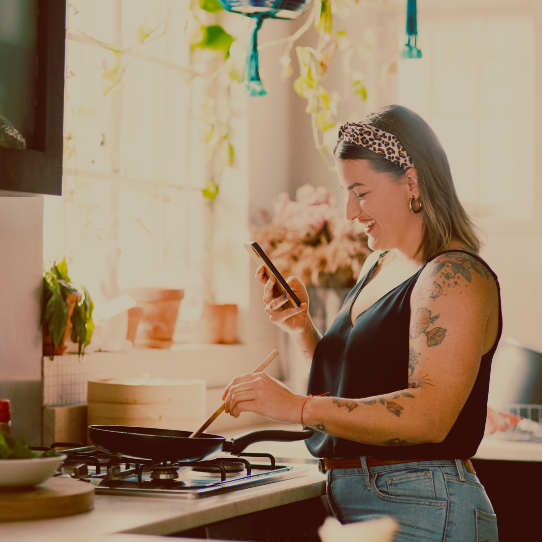 Woman cooking a healthy meal in her kitchen while reading a recipe on her phone.