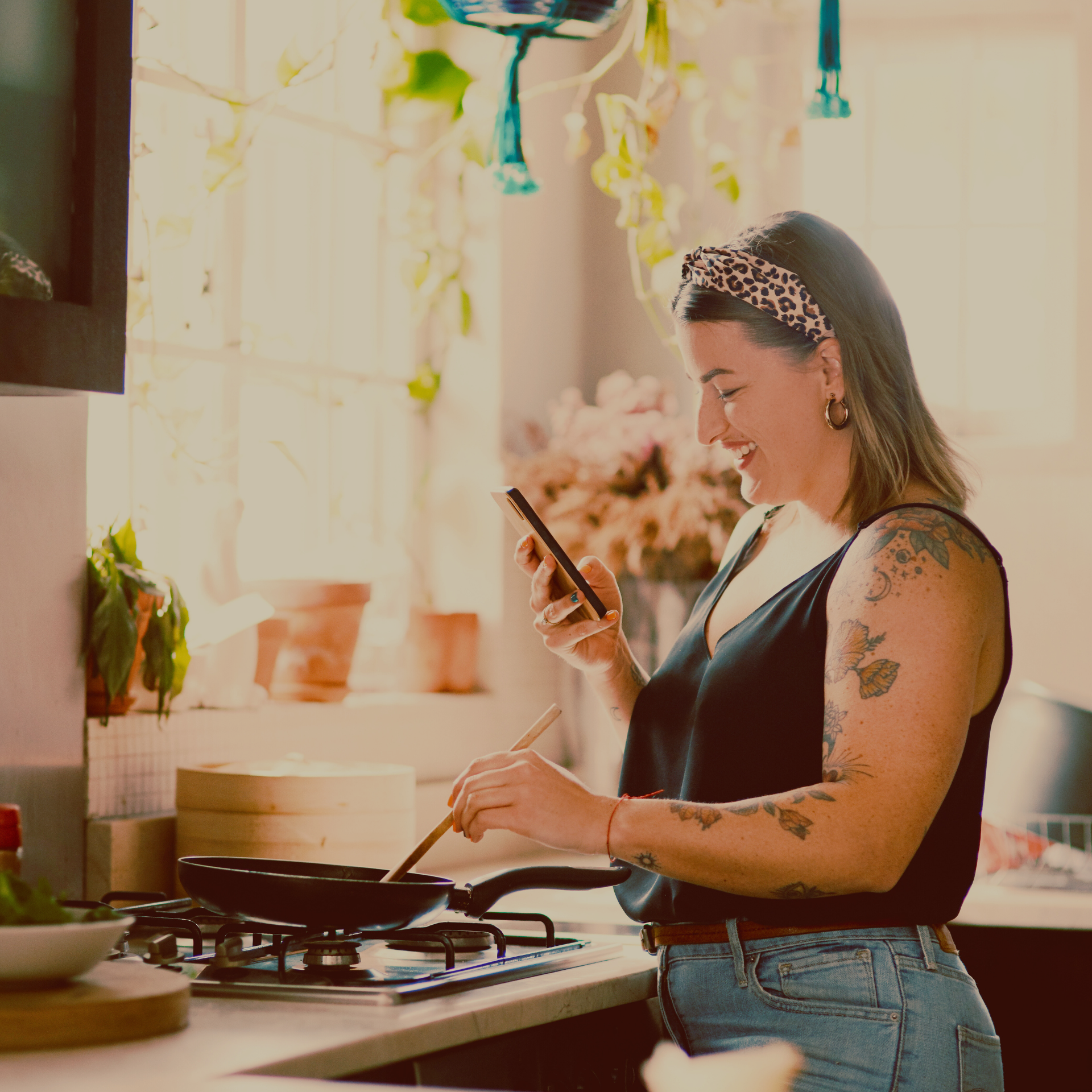 Woman cooking a healthy meal in her kitchen while reading a recipe on her phone.